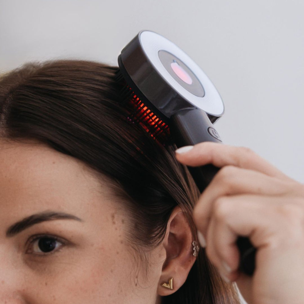 Person using a hair care device on their head with a neutral background